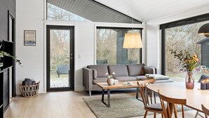 A modern living room with a sofa, coffee table, and dining area. - Awesome home in Stege with kitchen (Stege)
