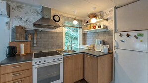 A compact kitchen with a stove, oven, sink, and refrigerator. There are wooden cabinets, a clock, and a window with blinds. - 2 bedroom beautiful home in Höör (Höör)