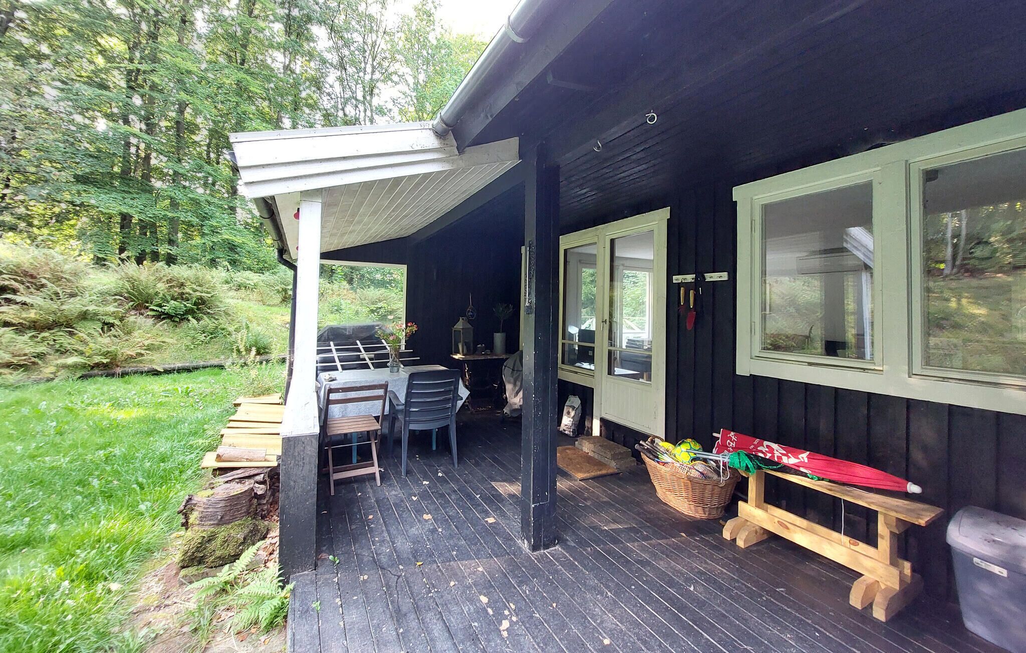 A wooden deck with a covered area, a table with chairs, and a bench.