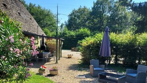 A garden with a thatched-roof structure, outdoor seating, and a gravel path. - Charming Gîte in Périgord Noir, Close to the Reference Sites of the Dordogne (Archignac)