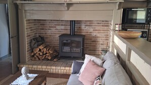 A cozy living room with a fireplace, a sofa, a coffee table, and a kitchen area with a microwave. - Charming Gîte in Périgord Noir, Close to the Reference Sites of the Dordogne (Archignac)