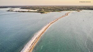 An aerial view of a coastal area with a long sandy beach, a small island with buildings, and a clear view of the water. - Krec'h Briand - PLEUBIAN (PLEUBIAN)