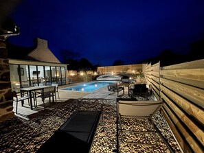 A backyard with a swimming pool, outdoor furniture, and a stone pathway.