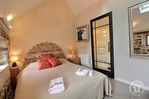 A hotel room with a bed, a nightstand, a lamp, a radiator, and a mirror.