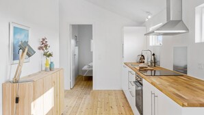 Une cuisine moderne avec un plancher en bois, des armoires blanches et une hotte de cuisinière en acier inoxydable.