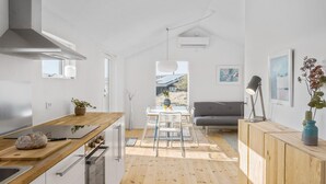 Une cuisine moderne avec un plan de travail en bois, un coin repas avec une table et des chaises, et un canapé gris en arrière-plan.