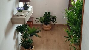 A hallway with a wooden floor, a desk with a lamp, and potted plants. - Alto Santiago (San Vicente de la Barquera)