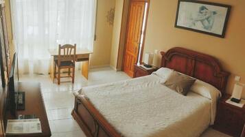A bedroom with a large bed, a wooden nightstand, a desk, and a chair.