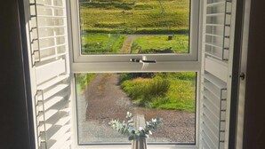 Una ventana con vistas a un paisaje verde y un sendero de grava.