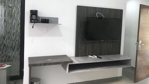 Een moderne woonkamer met een ingebouwde televisie, een koffiezetapparaat en een zithoekje.