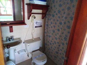 Une petite salle de bain équipée de toilettes, d’un lavabo et d’un téléphone.