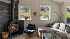 Une pièce chaleureuse avec une cheminée, un canapé confortable et deux fenêtres donnant sur l’extérieur.