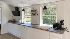 Une cuisine moderne avec des meubles blancs, une grande fenêtre et un appareil à café intégré.