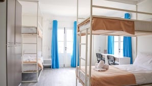 A bunk bed room with a desk and chair, a wardrobe, and a door with curtains. - AM Hostel (Sliema)