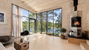 Ein geräumiges Wohnzimmer mit großem Kamin, Holzdielen und Blick auf einen See.
