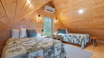 Ett mysigt sovrum i en stuga med två sängar, ett fönster och en luftkonditioneringsanläggning.
