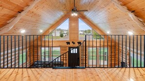 A spacious attic room with wooden walls and a sloped ceiling. - Waterfront Log Cabin • Sauna • Game Room • Pontoon & Snowmobile Access (Hancock)