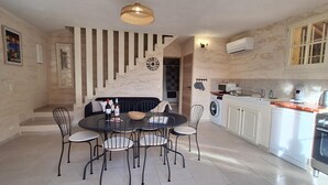 A modern kitchen with a dining area, featuring a round table, chairs, a clock, and a built-in oven. - Cinsault - LA Cadiere D'azur (LA CADIERE D'AZUR)