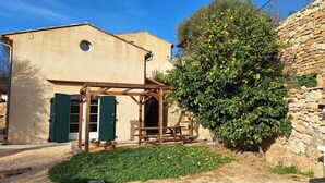 A rustic building with a stone wall, a wooden pergola, and a well-maintained garden. - Cinsault - LA Cadiere D'azur (LA CADIERE D'AZUR)