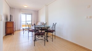 A dining area with a round glass table and four chairs, a wooden cabinet, and a sliding glass door leading to a balcony. - Gorgeous apartment in Torrevieja (Torrevieja)