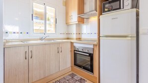 A compact kitchen with a built-in oven, a microwave, and a refrigerator. - Gorgeous apartment in Torrevieja (Torrevieja)