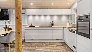 A modern kitchen with white cabinetry, a wooden countertop, and built-in appliances.