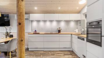 Une cuisine moderne avec des meubles blancs, un plan de travail en bois et des appareils électroménagers intégrés.