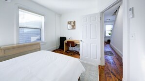 Een slaapkamer met een bed, een bureau en een stoel.