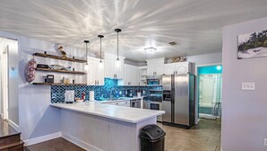 Een moderne keuken met witte kasten, een blauwe achterwand en roestvrijstalen apparatuur.