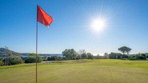 A golf course with a flag, a clear sky, and a sun in the background. - Cap Esterel Saint Raphael T2 vue mer + Parking (Saint-Raphaël)