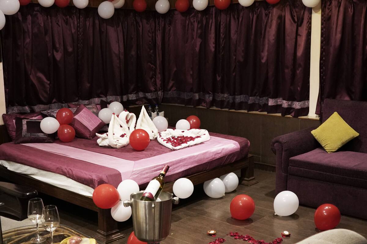 A room with a bed, a sofa, and a table with a bottle of champagne.