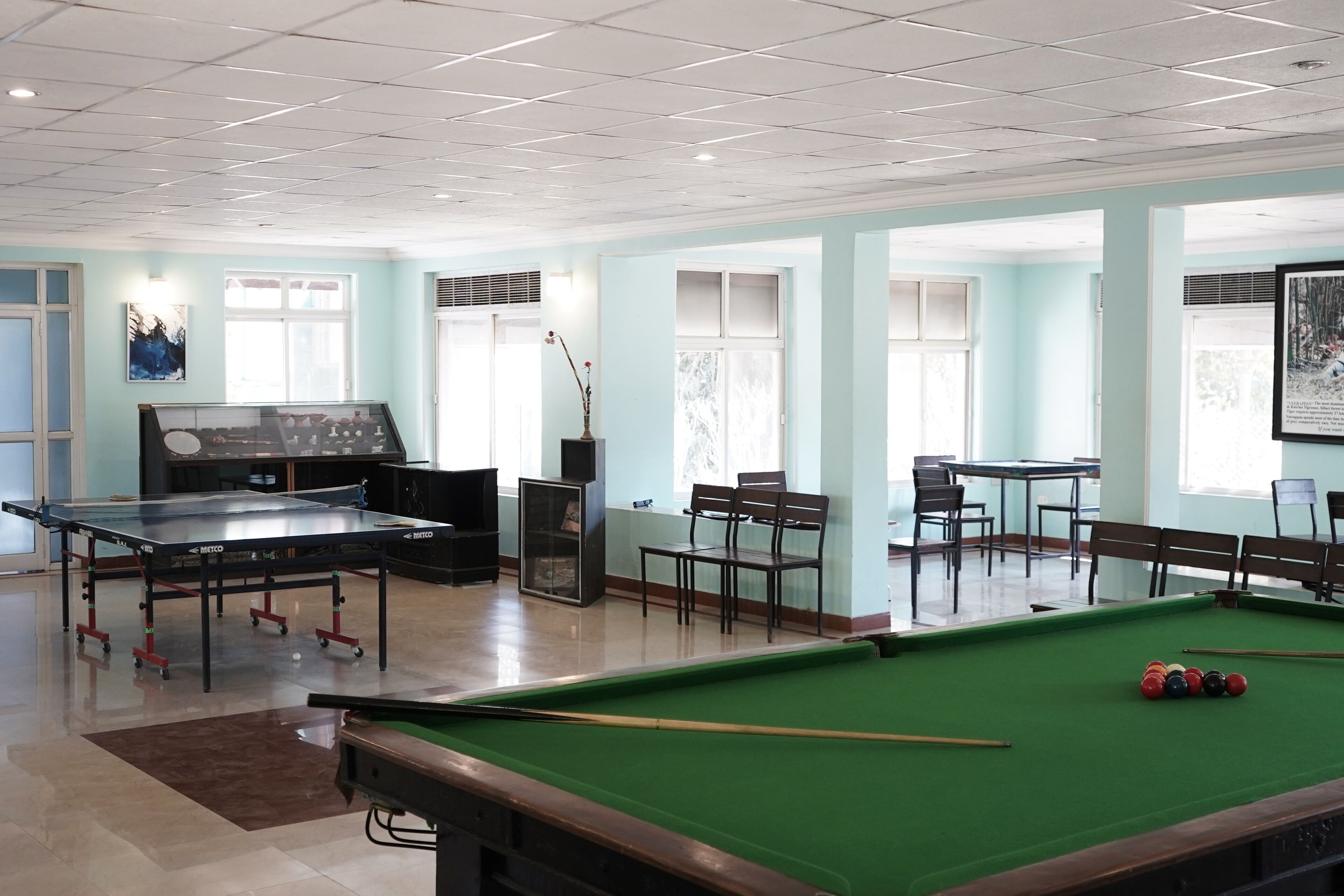 Una sala de billar con mesa de billar, mesa de ping pong y zonas de estar.