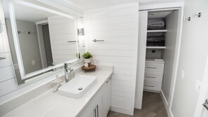 Une salle de bain moderne avec un meuble-lavabo blanc, un grand miroir et un meuble de rangement intégré.