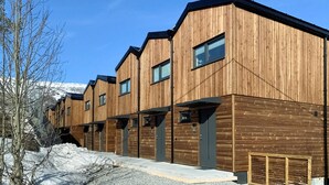Une rangée de bâtiments en bois, dotés de grandes fenêtres et d’un toit plat.