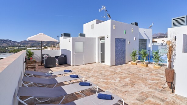 A rooftop terrace with lounge chairs, a table with bottles, and a view of the landscape. - Studio Apartment "Nerja Boutique Street Level B1" with Shared Pool & Wi-Fi (Nerja)