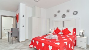 Un dormitorio moderno con una cama, mesitas de noche, un escritorio y una silla.