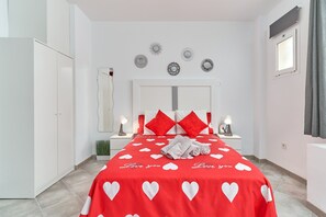 A bedroom with a bed, two bedside tables, a mirror, and a wardrobe.