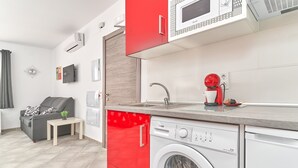 Un espacio habitable compacto con lavadora, cafetera y sofá.