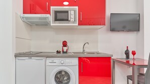 Cocina compacta con lavadora, microondas y televisor.