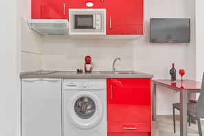 Une cuisine compacte équipée d’un lave-linge, d’un four à micro-ondes et d’un téléviseur.