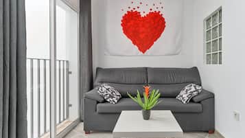 A living room with a grey sofa, a white coffee table, and a red heart artwork on the wall.