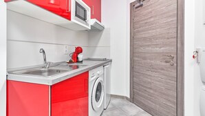 A compact kitchen with a washing machine, a microwave, and a red cabinet.