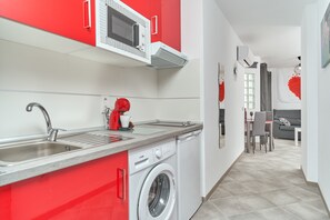 A compact kitchen with a washing machine, a microwave, and a sink.