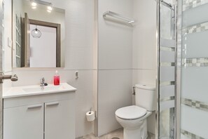 Un baño moderno con lavamanos, espejo, inodoro y cabina de ducha de vidrio.