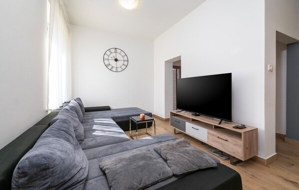 Uma sala de estar moderna com um amplo sofá de canto, uma televisão de tela plana e design minimalista.