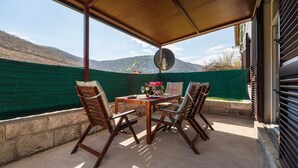 An outdoor patio with a table and chairs, a satellite dish, and a view of mountains.