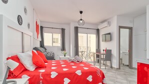 Une chambre moderne avec une couvre-lit à motifs de cœurs rouges, un bureau et un coin repas offrant une vue agréable.