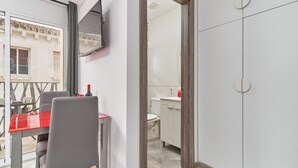 Une chambre moderne avec une table à manger, des chaises, un téléviseur fixé au mur et une vue sur le balcon extérieur.