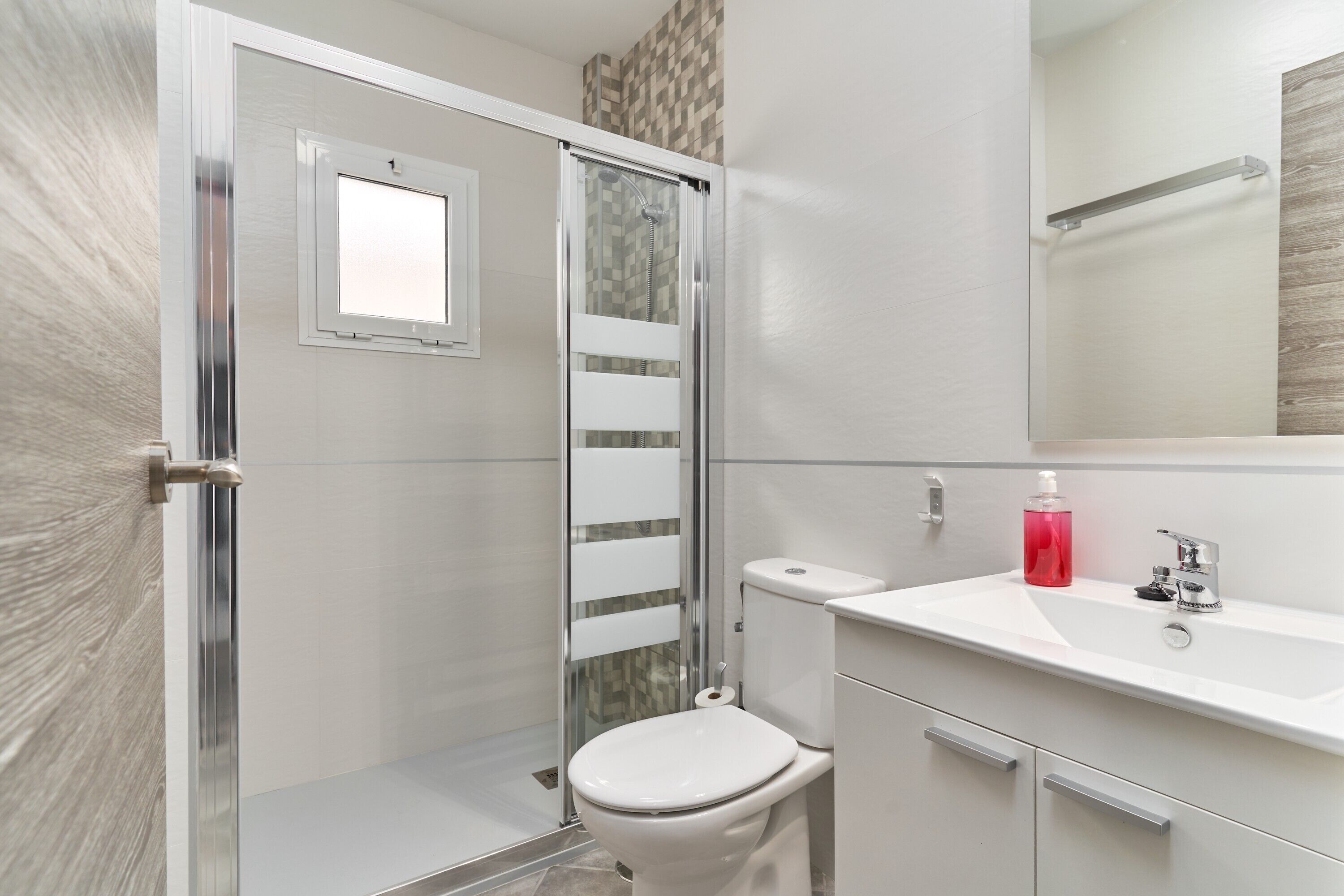 Une salle de bain équipée d’une douche, de toilettes, d’un lavabo et d’un miroir.