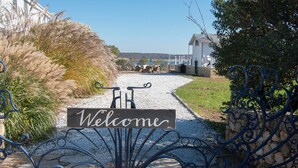 Un camino de grava que lleva a un edificio blanco con un cartel de 'Welcome' en la entrada.